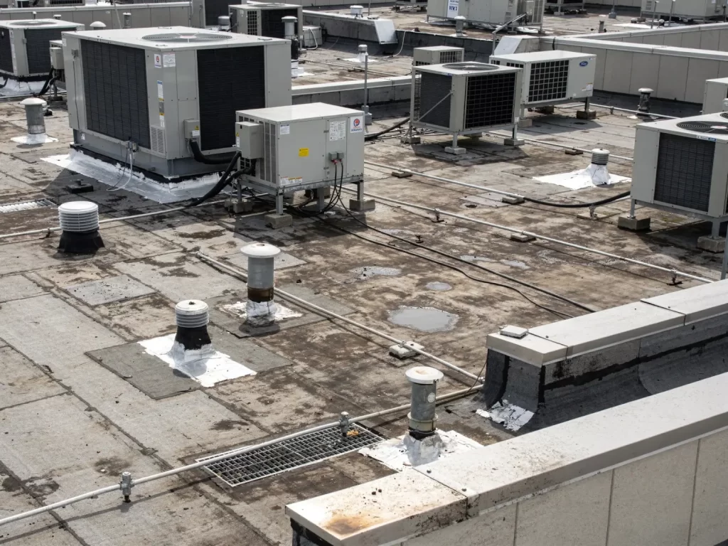 Commercial flat roof with multiple HVAC units, vents, drains, and penetrations showing roofing complexity and cost factors