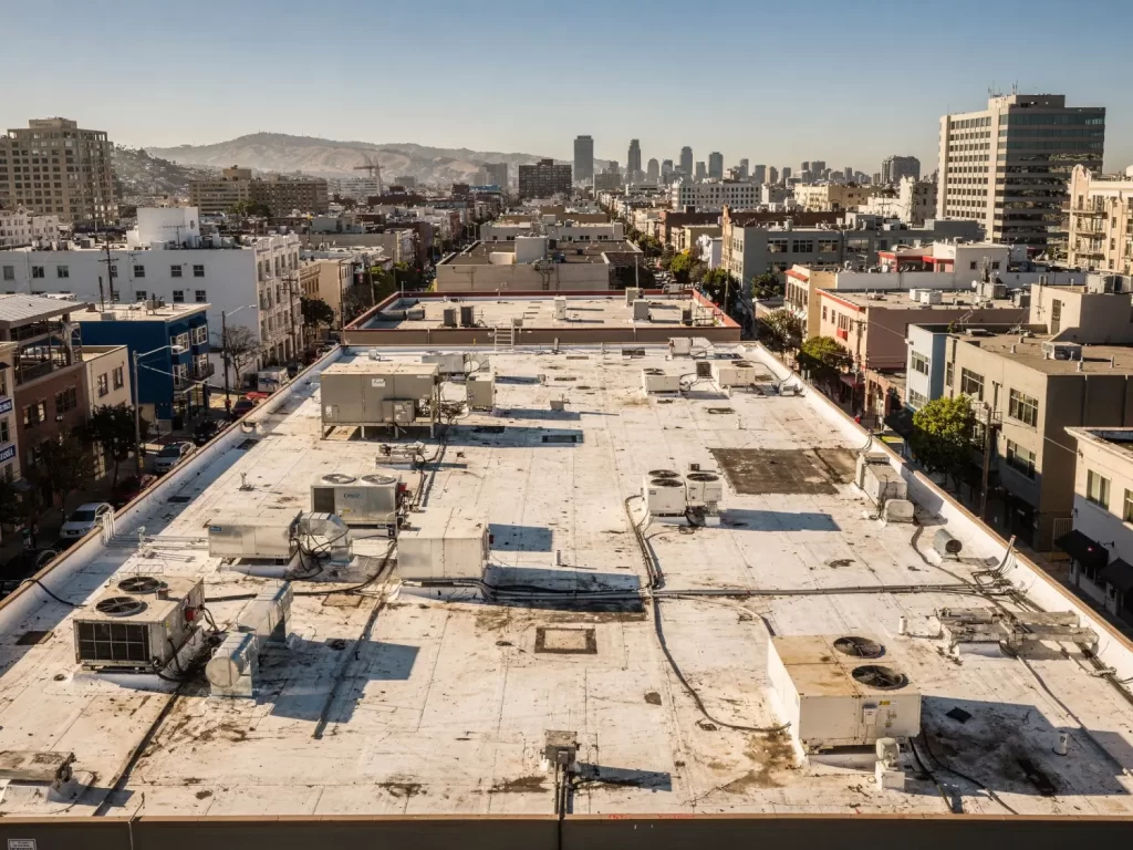 Flat commercial roof in dense California urban area with surrounding buildings and city streets