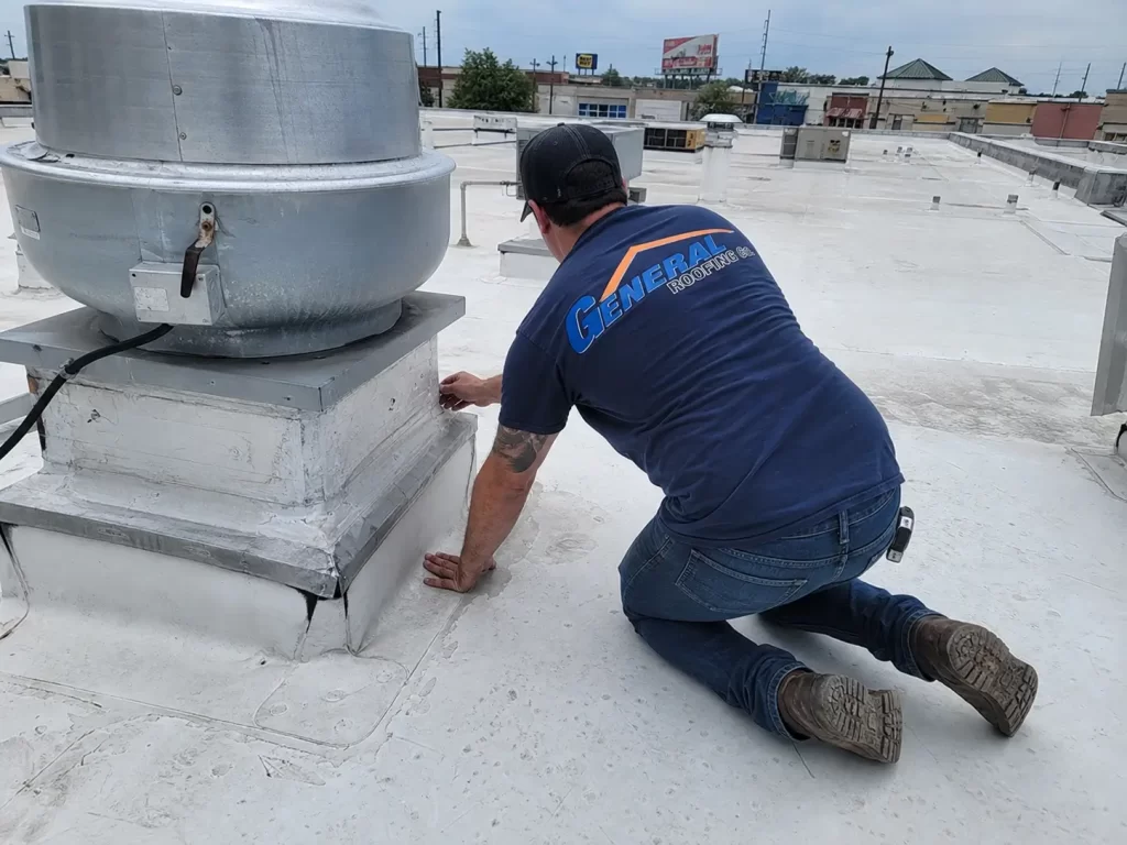 General Roofing roofer inspecting PVC roof flashing around a restaurant rooftop exhaust fan