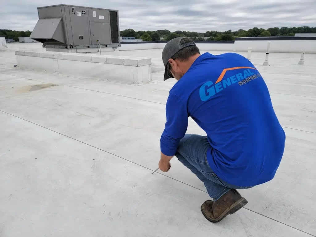 General Roofing roofer inspecting seams on a white TPO commercial roof