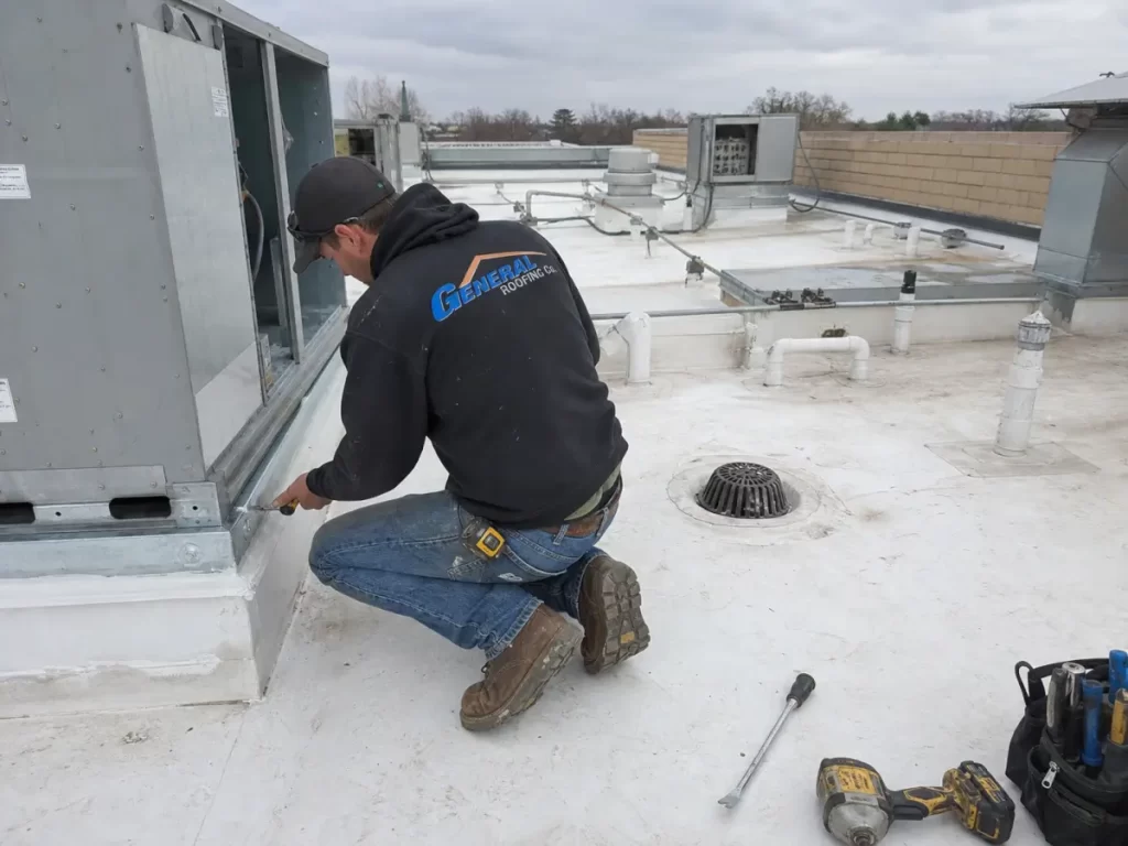 General Roofing roofer checking rooftop equipment and flashing details that raise PVC roof installation cost