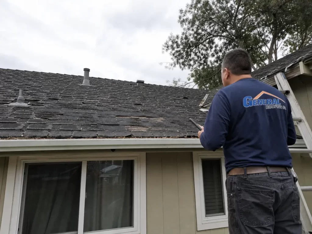 General Roofing technician inspecting a worn residential roof with widespread shingle damage and visible replacement warning signs.